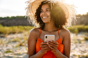 Wall Mural - Young happy woman using mobile phone the beach