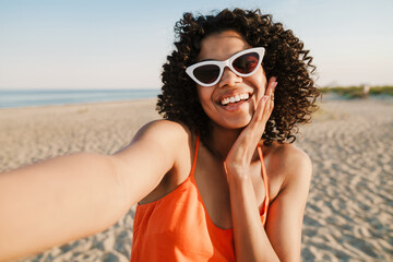 Wall Mural - African woman taking a selfie by camera at the beach