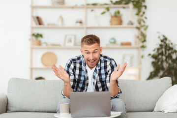 Excited young man feeling ecstatic using laptop