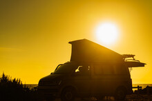 Camper Van With Tent On Roof At Sunset