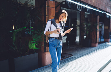 Wall Mural - Laughing woman browsing smartphone on sidewalk