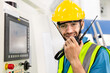 © winnievinzence - Portrait of male worker talking on radio phone or walkie-talkie with colleague to controlling work in front of industry machine at industrial factory. technology and communication at workplace