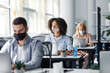 © Prostock-studio - Generate an idea and inspiration for work during covid-19. Focus on african american woman in protective mask looks out the window at workplace with laptop and antiseptic