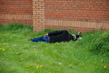 a drunk passed out on a patch of grass in liverpool, uk