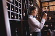 © LIGHTFIELD STUDIOS - Selective focus of sommelier looking at wine in glass near racks with bottles