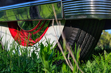 Close Up Detail Of Classic, Vintage, Luxury Car's Rear Wheel Parked In Grass With Whitewall Tires, Red Wheel Chrome Hubcap And Retro Wheel Guard