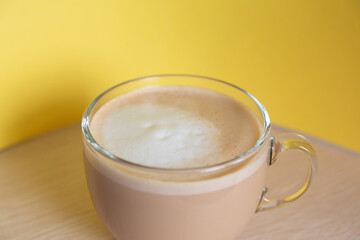 mug of coffee with milk and froth on a yellow background. Energy and cheerfulness in the morning.