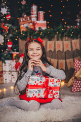 Happy girl holding a box with a gift in her hands. On the background of boxes with New Year's gifts