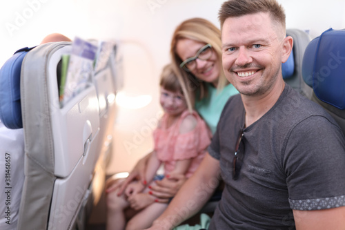 Fotografía Family dad mom daughter are sitting in seats of plane and smiling