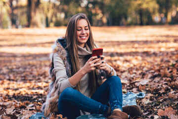 Young woman in the park using smartphone  and laughing