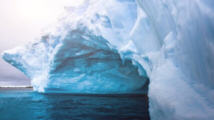 Wall Mural - glacier with natural cave inside swaying on the water in open ocean in antarctica. dramatic winter l