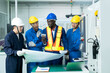 © godji10 - Multiethnic industrial engineers have to consult with technician while using a blueprints. Supervisor, Worker with hard hat working in manufacturing factory on business day. Concept of race equality.
