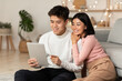 © Prostock-studio - Happy Korean Couple Using Tablet Computer Sitting At Home
