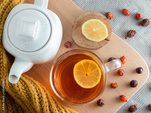 autumn still life. white teapot, tea in a mug, sliced lemon and dried rose hips