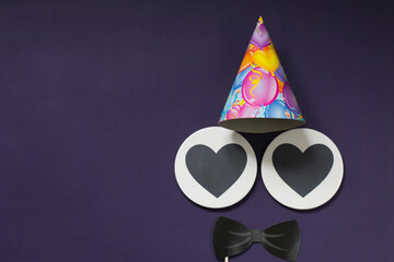 For a holiday for men. Postcard on a purple background - black bow tie, festive hat, two hearts for text. Copy space.