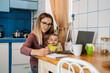 © irissca - Work from home. Young mother with baby girl working at home using laptop on kitchen background Young woman feeding her baby, talking on mobile phone, looking at laptop at her home working place