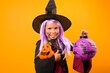 © Marina - Smiling little girl in a witch costume and heloin lanterns. Person posing on a yellow background in the studio. Copy space. High quality photo