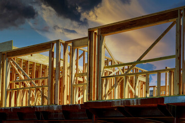 New construction home residential construction home framing against a dramatic sunset sky bright horizon