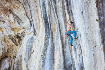 Wall Mural - Caucasian man climbing challenging route on cliff