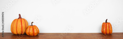 Fotografía Wooden autumn pumpkin decorations on a wood shelf against a white wall background