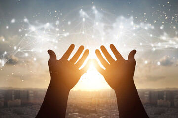 Technology concept: Silhouette many people raised hands over city sunset background