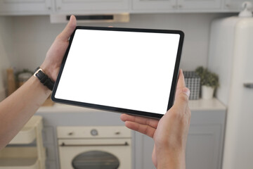 Cropped shot of hand holding blank screen of tablet at home in kitchen. For graphic display montage.