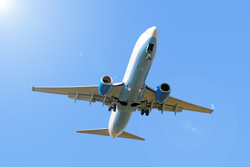Wall Mural - modern airplane flying high against blue sky background. Passenger plane landing. Jet aircraft in air with gear and flaps extended. Belly view of business jet. Aviation wallpaper