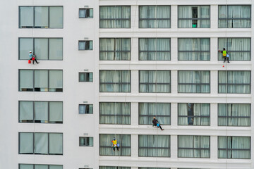 Asian industrial worker cleaning windows of a modern building.