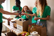 © alfa27 - active young people enjoys volunteering at food and clothes bank, voluntary company. diverse people working in voluntary company with friends putting food for donation into boxes