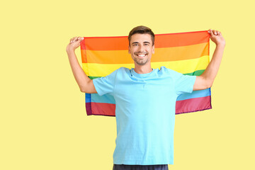 Wall Mural - Young man with LGBT flag on color background