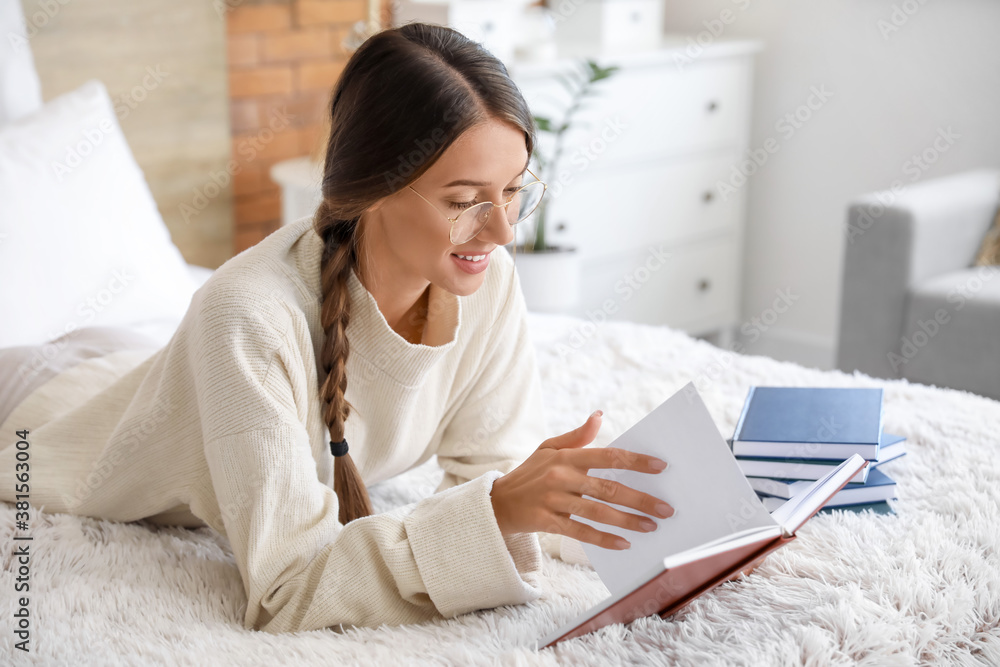 Beautiful young woman reading book at home