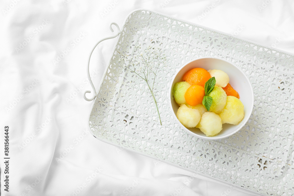 Bowl with tasty melon balls on bed
