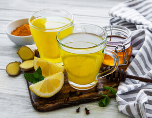 Wall Mural - Energy tonic drink with turmeric, ginger, lemon and honey on a white wooden background