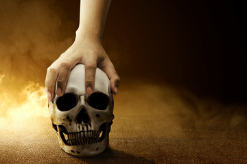 Poster - Hand holding a human skull on the concrete floor with smoke