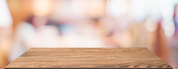 Aufkleber - Empty wood table with blur people in coffee shop background bokeh light and leaf foreground,Mockup for display or montage of product,Banner for advertise on online media,business presentation