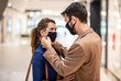 © Sanja - Attractive fashionable man adjusting face mask on his girlfriend while standing in shopping mall during corona virus.