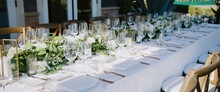 Wedding Banquet With Clear Glass Goblets And Wine Glasses, White Plates And Gold Forks And Decorations