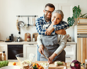 Happy housewife with adult son preparing healthy dinner at home.