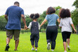 © CandyRetriever  - Happy mixed race family parents with cute child girl holding hands and walking together in the park. Father and mother with two daughter enjoy and having fun in summer outdoor holiday vacation.