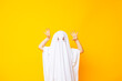 Little kid wearing cute halloween ghost costume on yellow background