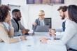 © Sanja - A group of business partners sit in a conference room, employees suggest new ideas in making a profit, others listen
