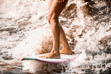 Close-up Of Beautiful Athletic Tanned Legs Of Woman Riding Wave On Surf Style Wakeboard