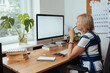 © Girts - Woman working from home office. Computer with blank empty screen for copy space and information. A businesswoman from behind shoulder view. A creative entrepreneur. Mockup pc screen remote developer