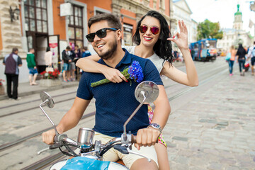 young beautiful hipster couple riding on motorbike city street, summer europe vacation, traveling, romance, smiling, happy, having fun, sunglasses, stylish outfit, together in love, adventures, date