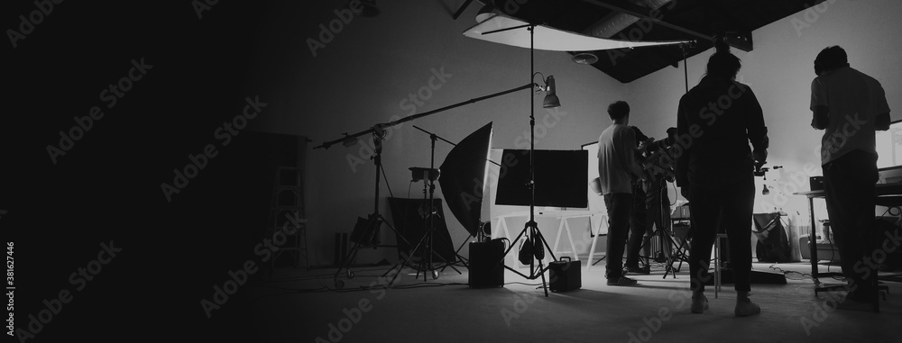 Behind the scene of photo shooting and production set up in the big studio. Professional crew team working and camera equipment in silhouette. such as light box, tripod, flashlight. and copy space. - obrazy, fototapety, plakaty 
