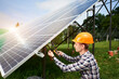 Engineer in helmet connects solar panels on a green plantation. Green ecological power energy generation. Modern solar, great design for any purposes. Business concept.