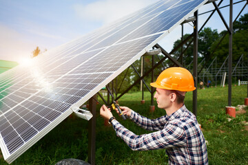 Wall Mural - Engineer in helmet connects solar panels on a green plantation. Green ecological power energy generation. Modern solar, great design for any purposes. Business concept.