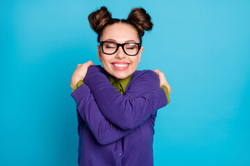 Photo of pretty overjoyed student lady two buns eyes closed hugging herself motivation before test examination wear specs shirt collar violet sweater isolated blue color background