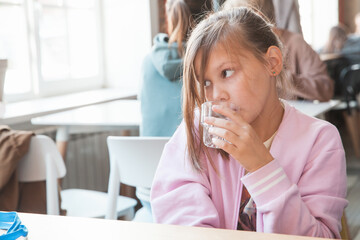 Blond Caucasian little girl drinks water