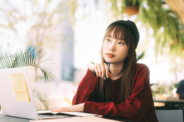 Wall Mural - Asian teenager college student woman using laptop for work and study at cafe on day.